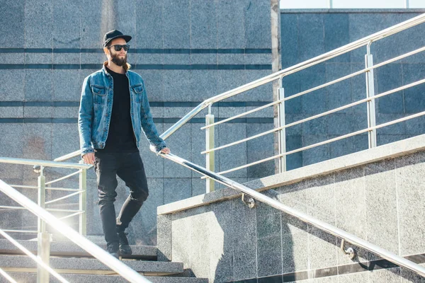 Hipster man met zonnebril en een zwarte pet in een stad — Stockfoto