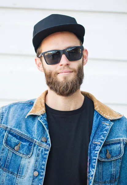 Modaya uygun kot elbise giyen gülümseyen yakışıklı hipster adam