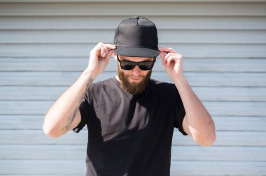Siyah T-shirt ve yeri olan siyah bir şapka giyen hipster adam