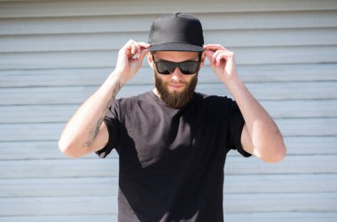 Siyah T-shirt ve yeri olan siyah bir şapka giyen hipster adam