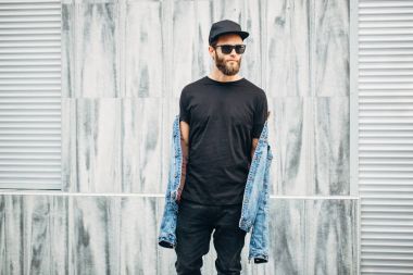 Siyah kot, tişört ve bir beyzbol yürüyen hipster adam 