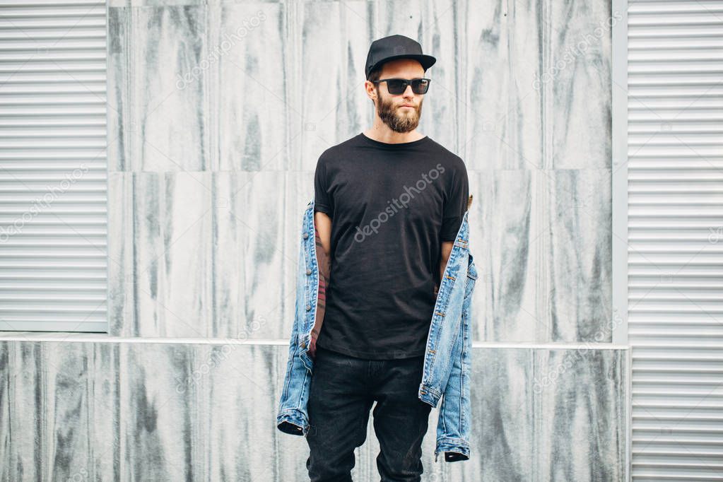Hipster man walking wearing black jeans, t-shirt and a baseball 