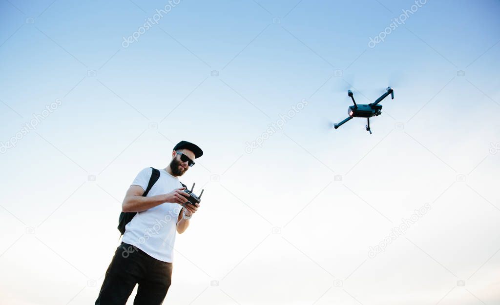 Man controlling a dron via a a controller and flying. man playin