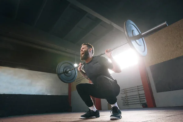 Atleet man met een baard uitoefenen in een crossfit fitnessruimte — Stockfoto