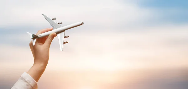 Dziecko trzyma w rękach samolot i latające nad zachód słońca backgro — Zdjęcie stockowe