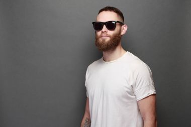 Hipster yakışıklı erkek model gri arka plan üzerinde logo veya tasarım alanı olan beyaz boş t-shirt giyen sakallı