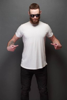 Hipster yakışıklı erkek model gri arka plan üzerinde logo veya tasarım alanı olan beyaz boş t-shirt giyen sakallı