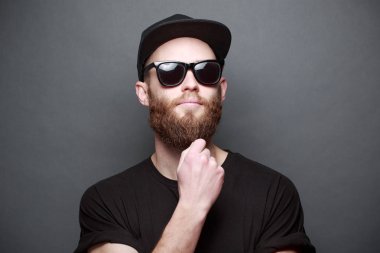 Hipster yakışıklı erkek model gri arka plan üzerinde logo veya tasarım alanı olan siyah boş t-shirt giyen sakallı