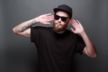 Hipster yakışıklı erkek model gri arka plan üzerinde logo veya tasarım alanı olan siyah boş t-shirt giyen sakallı