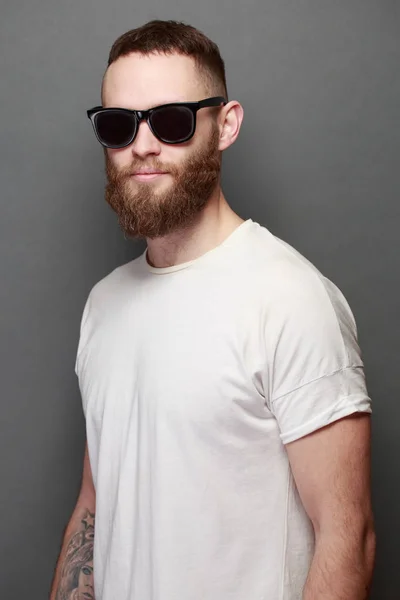 Hipster yakışıklı erkek model gri arka plan üzerinde logo veya tasarım alanı olan beyaz boş t-shirt giyen sakallı — Stok fotoğraf