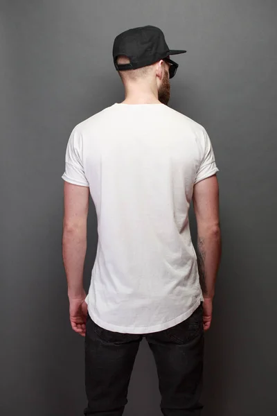 Modelo masculino bonito Hipster com barba vestindo t-shirt branca em branco com espaço para o seu logotipo ou design sobre fundo cinza — Fotografia de Stock