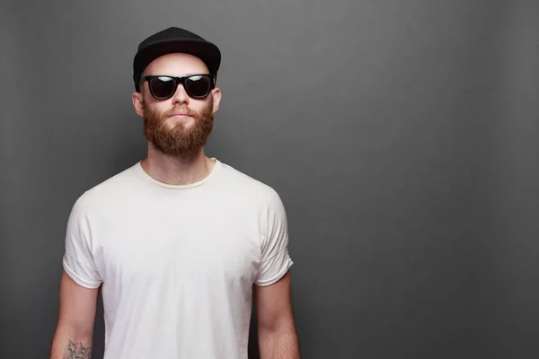 Όμορφος αρσενικό μοντέλο hipster με γένια, φορώντας λευκό κενό t-shirt με χώρο για το λογότυπο ή το σχεδιασμό σας πάνω από το γκρίζο φόντο — Φωτογραφία Αρχείου
