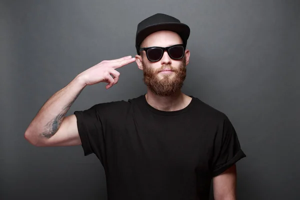 Hipster stilig manlig modell med skägg bär svart blank t-shirt med plats för din logotyp eller design över grå bakgrund — Stockfoto