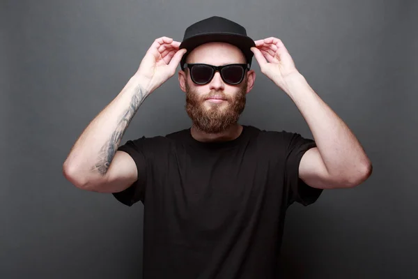Hipster guapo modelo masculino con barba con camiseta en blanco negro con espacio para su logotipo o diseño sobre fondo gris — Foto de Stock
