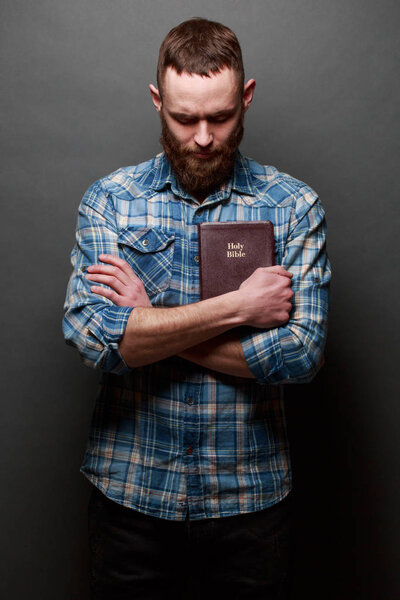 Один человек читает и перелистывает Библию в темной комнате над текстурой
