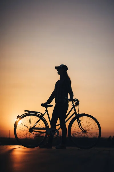 Donna in bicicletta in città durante il tramonto — Foto Stock