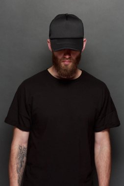 Hipster yakışıklı erkek model siyah boş tişört ve siyah beysbol şapkası için logo veya tasarım alanı ile rahat kentsel tarzı giymiş sakallı