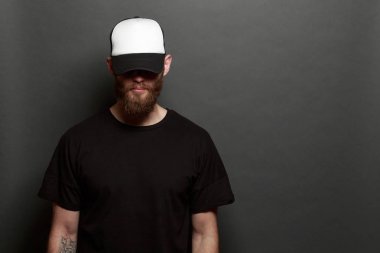 Siyah kot pantolon, tişört ve beyaz beysbol şapkası giyen yürüyen hipster adam