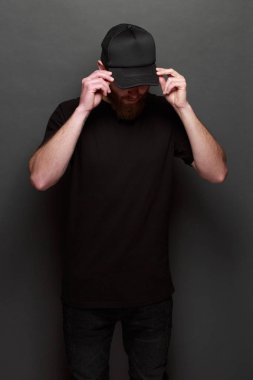 Hipster yakışıklı erkek model siyah boş tişört ve siyah beysbol şapkası için logo veya tasarım alanı ile rahat kentsel tarzı giymiş sakallı
