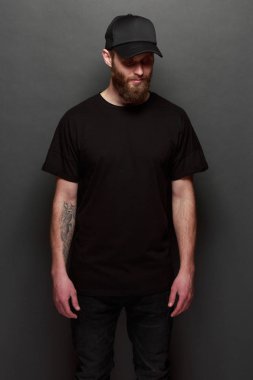 Hipster yakışıklı erkek model siyah boş tişört ve siyah beysbol şapkası için logo veya tasarım alanı ile rahat kentsel tarzı giymiş sakallı