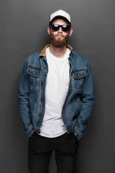 Hipster handsome male model with beard wearing white blank t-shirt and a baseball cap with space for your logo or design in casual urban style — Stock Photo, Image