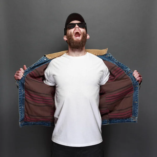 Hipster handsome male model with beard wearing white blank t-shirt and a baseball cap with space for your logo or design in casual urban style — Stock Photo, Image