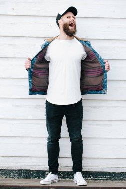 Siyah kot pantolon, tişört ve bir beyzbol şapkası giyen yürüyen hipster adam 