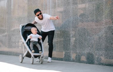 Babası bir bebek arabası ve bir bebek şehir sokaklarında yürüyüş