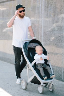 Babası bir bebek arabası ve bir bebek şehir sokaklarında yürüyüş