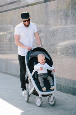 Babası bir bebek arabası ve bir bebek şehir sokaklarında yürüyüş