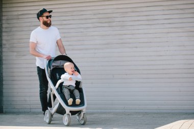 Babası bir bebek arabası ve bir bebek şehir sokaklarında yürüyüş