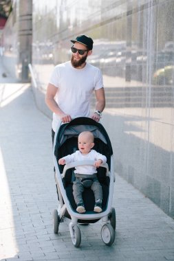 Babası bir bebek arabası ve bir bebek şehir sokaklarında yürüyüş