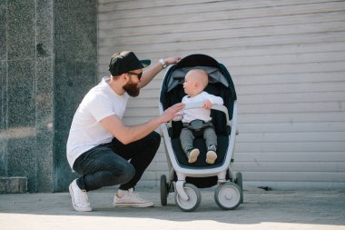 Babası bir bebek arabası ve bir bebek şehir sokaklarında yürüyüş