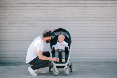 Babası bir bebek arabası ve bir bebek şehir sokaklarında yürüyüş