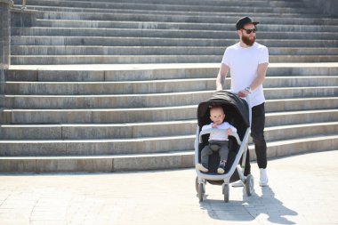 Babası bir bebek arabası ve bir bebek şehir sokaklarında yürüyüş