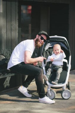 Babası bir bebek arabası ve bir bebek şehir sokaklarında yürüyüş