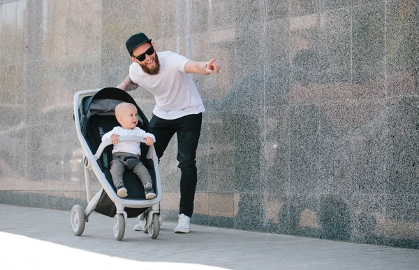 Babası bir bebek arabası ve bir bebek şehir sokaklarında yürüyüş