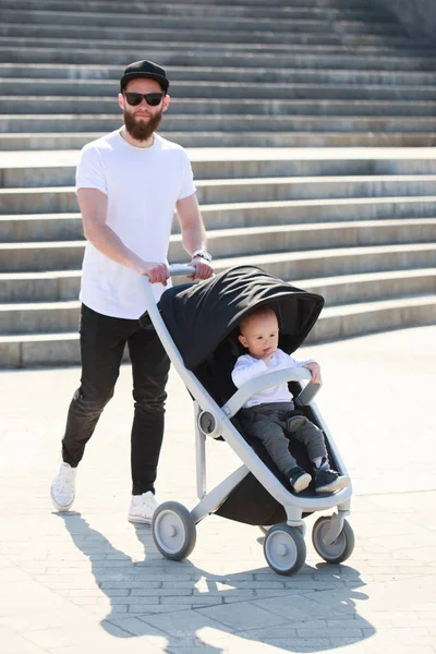 Father walking with a stroller and a baby in the city streets — Stock Photo, Image