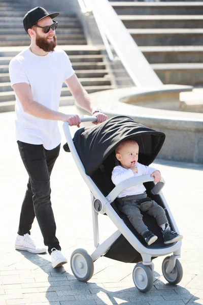 Father walking with a stroller and a baby in the city streets — Stock Photo, Image