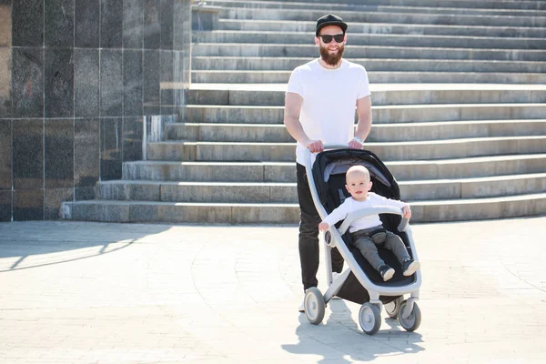 Отец гулял с коляской и ребенком по улицам города — стоковое фото