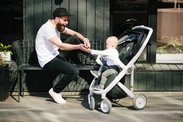 Pai andando com um carrinho e um bebê nas ruas da cidade — Fotografia de Stock