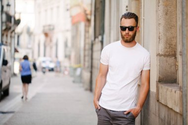 Sakallı, beyaz, boş tişörtlü, beysbol şapkalı, logonuz için yeri olan yakışıklı bir hippi mankeni.