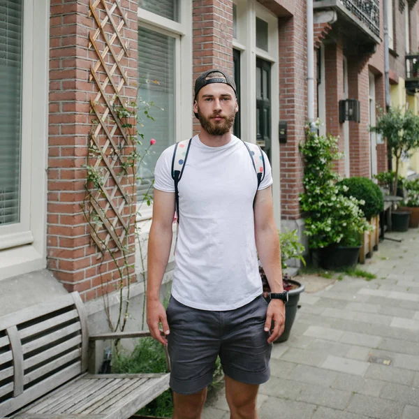 Hipster stilig manlig modell med skägg bär vit blank t-shirt och en baseball mössa med plats för din logotyp eller design i avslappnad urban stil — Stockfoto