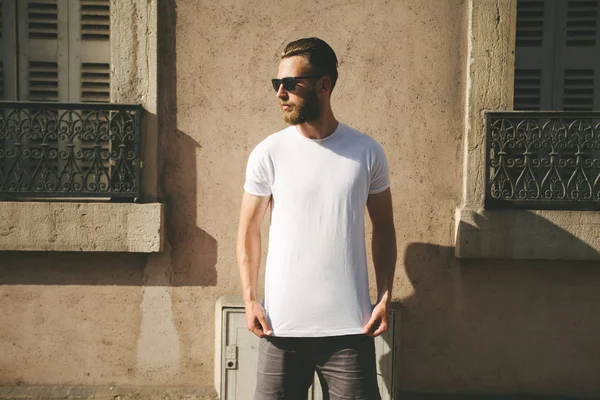 Modelo masculino bonito Hipster com barba vestindo t-shirt branca em branco e um boné de beisebol com espaço para o seu logotipo ou design em estilo urbano casual — Fotografia de Stock