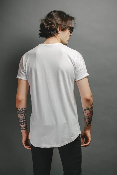 Hipster knap mannelijk model met bril in wit wit wit t-shirt en zwarte jeans met ruimte voor uw logo of ontwerp in casual urban stijl — Stockfoto
