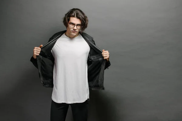 Hipster beau modèle masculin avec des lunettes portant un t-shirt blanc et un jean noir avec de l'espace pour votre logo ou votre design dans un style urbain décontracté — Photo