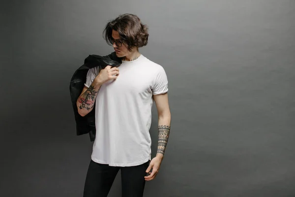 Modelo masculino bonito Hipster com óculos vestindo camiseta branca em branco e jeans pretos com espaço para o seu logotipo ou design em estilo urbano casual — Fotografia de Stock