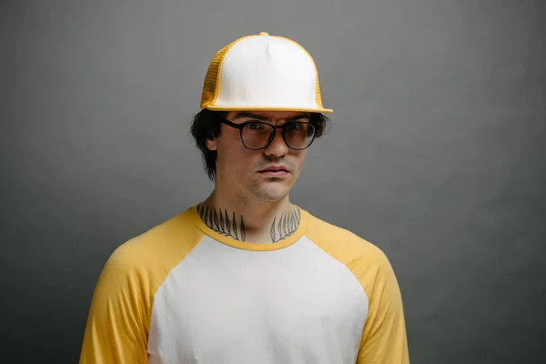 Hipster handsome male model wearing yellow blank baseball cap with space for your logo over gray background — Stock Photo, Image