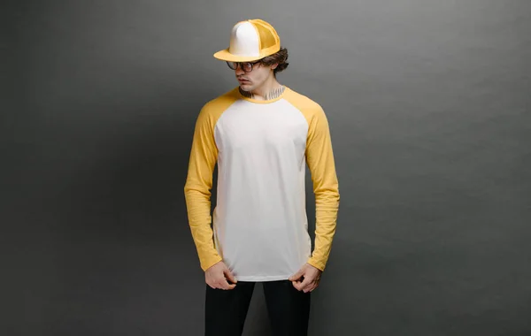 Man model with beard wearing white and yellow blank Long Sleeve Shirt for mock up and a baseball cap with space for your logo or design over gray background