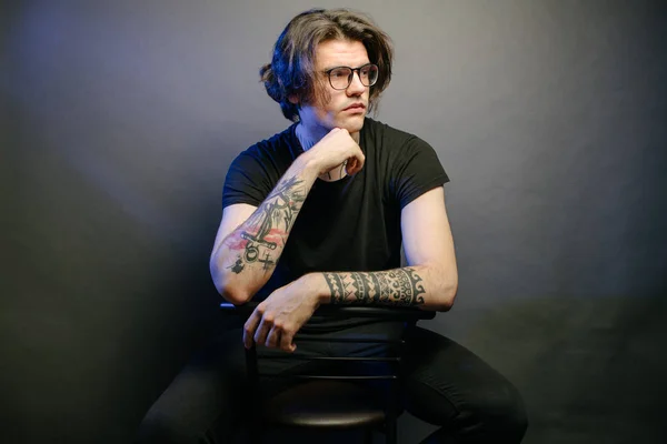 Retrato de un hombre Hipster con anteojos y tatuajes de cerca en la oscuridad — Foto de Stock